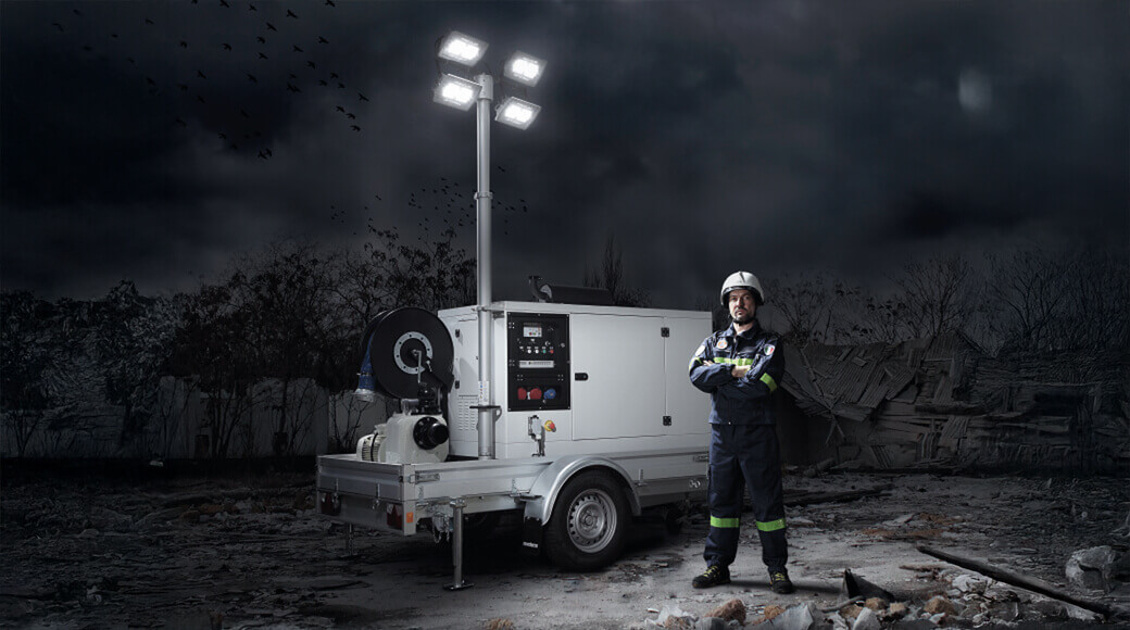 Euromacchine 2010. Emergency worker beside mobile lighting tower generator at night.