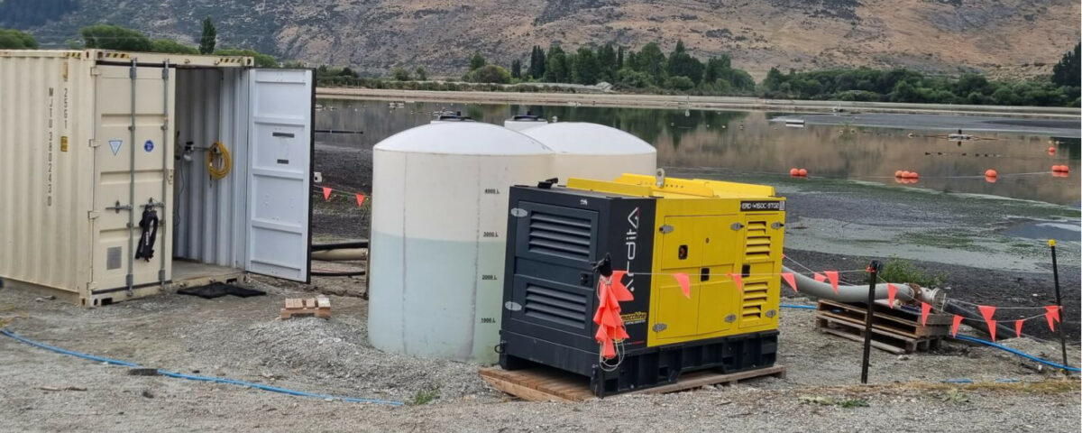 Euromacchine Ardita diesel pump beside storage tanks and site containers at a sewage-pond desludging project.